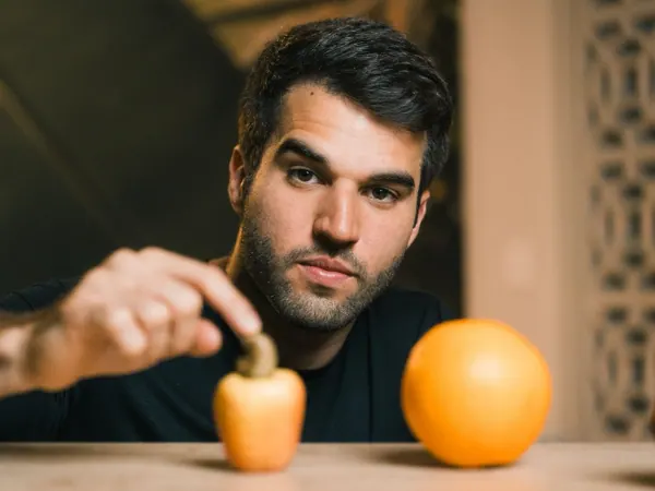 Mateus com uma laranja e uma fruta menor sobre a mesa